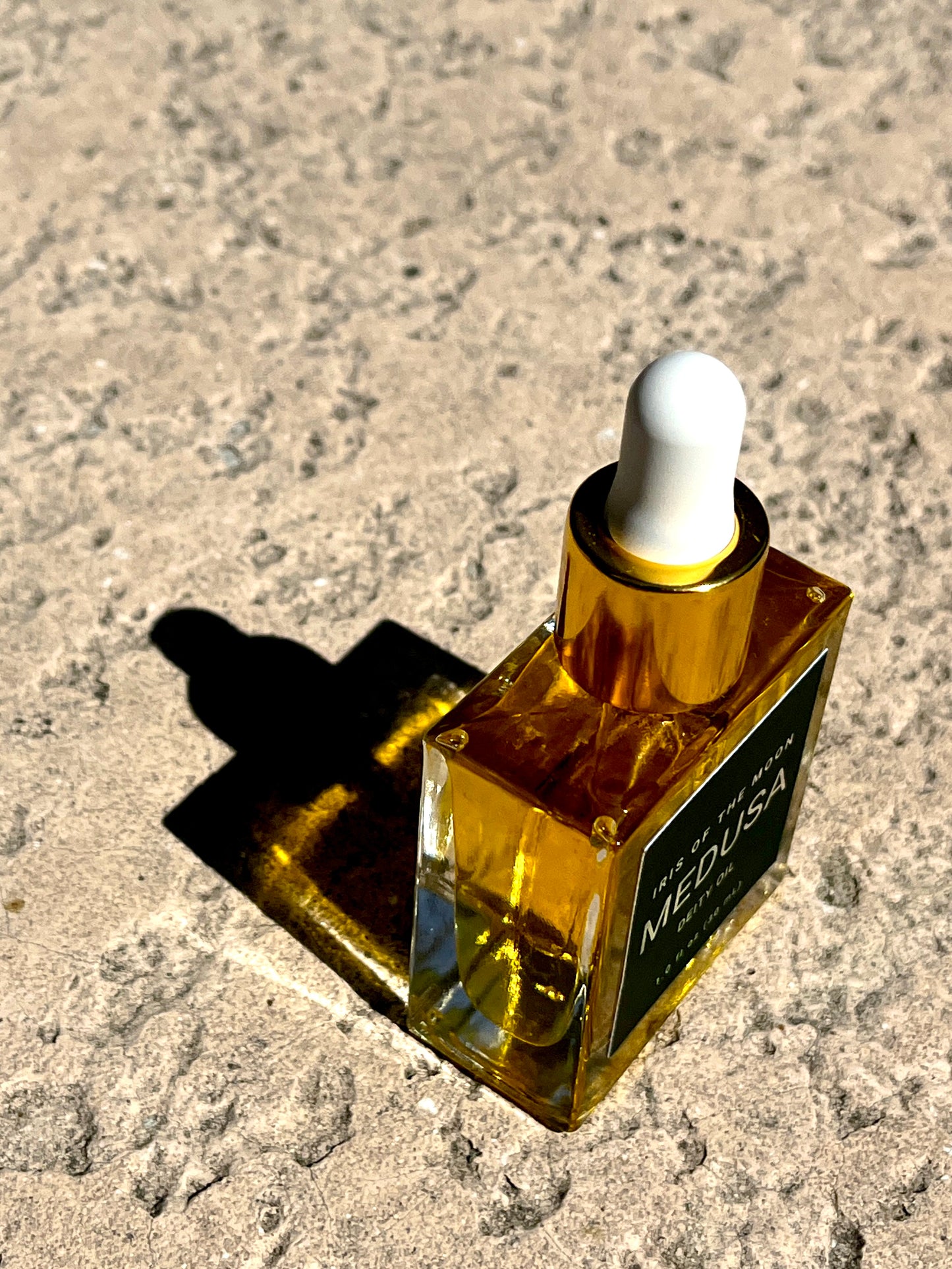 Gold bottle with dropper labeled 'Medusa' on a textured surface
