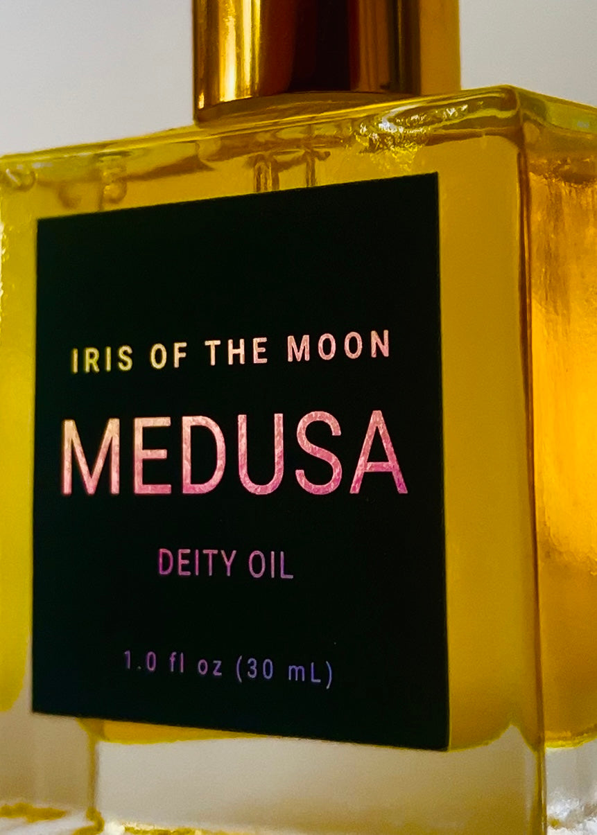 Gold bottle of 'Iris of the Moon Medusa Deity Oil' with a dark green label.