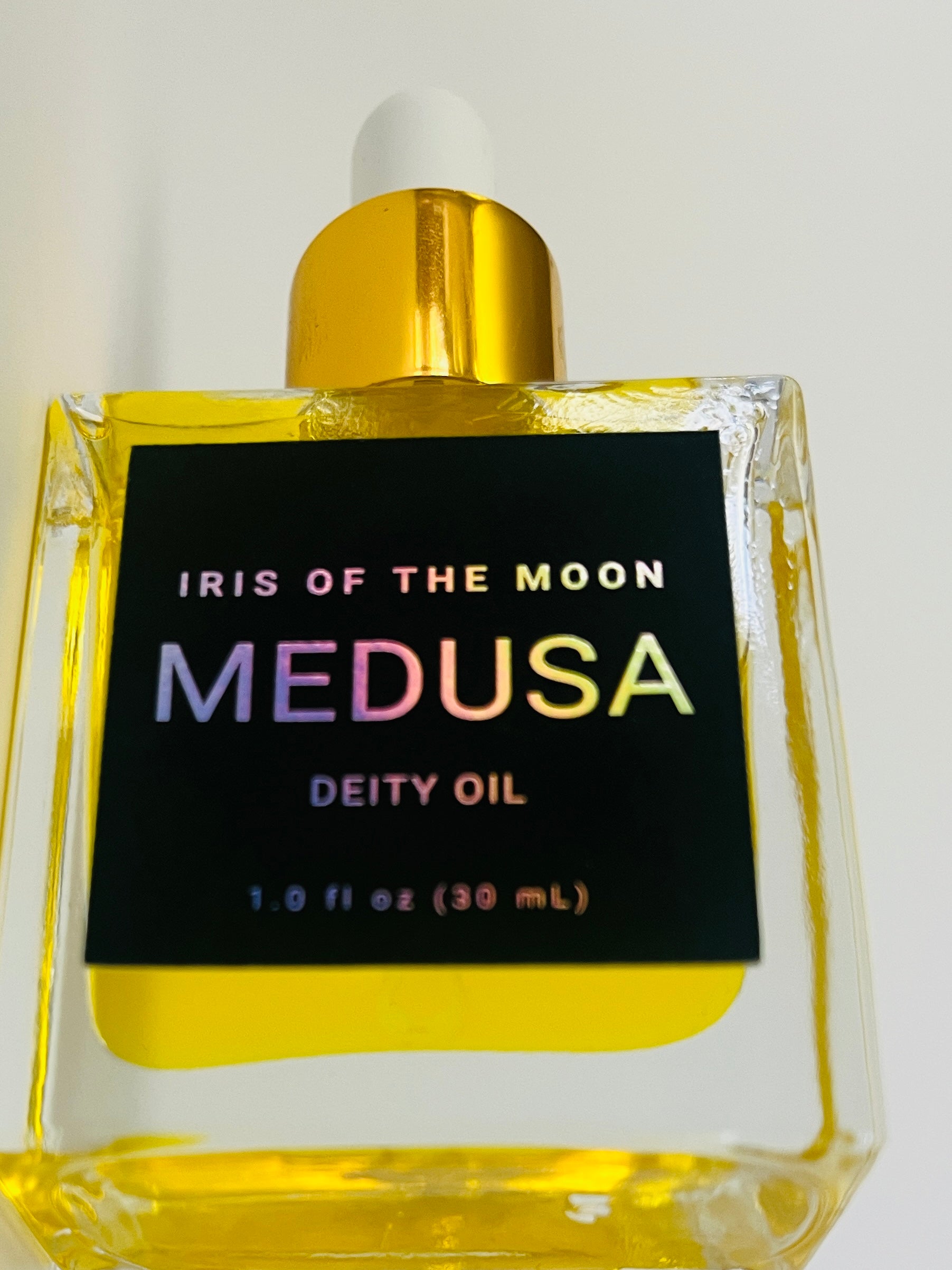 Bottle of 'Iris of the Moon Medusa Deity Oil' with a gold cap on a white background