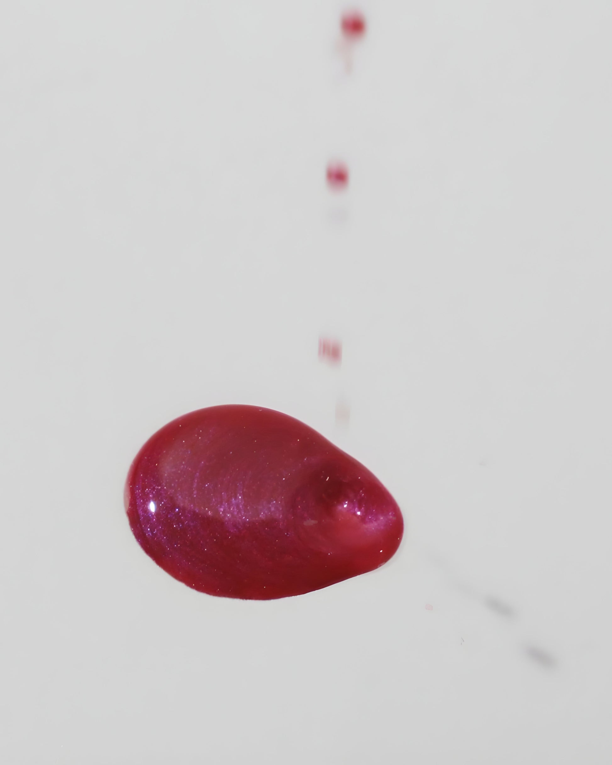 Magenta-colored oil spillng onto a white background