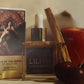 Lilith scented body oil with a palo santo stick, cherries, and an apple on a neutral background