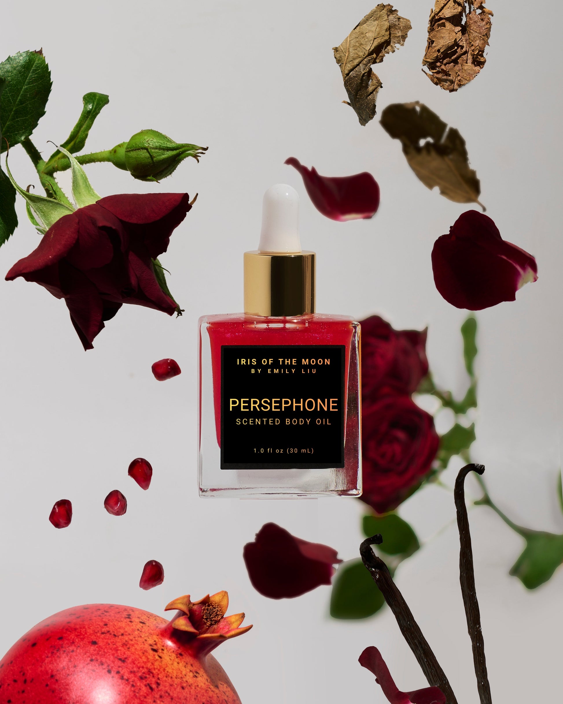Persephone scented body oil bottle with red roses and pomegranate on a light background