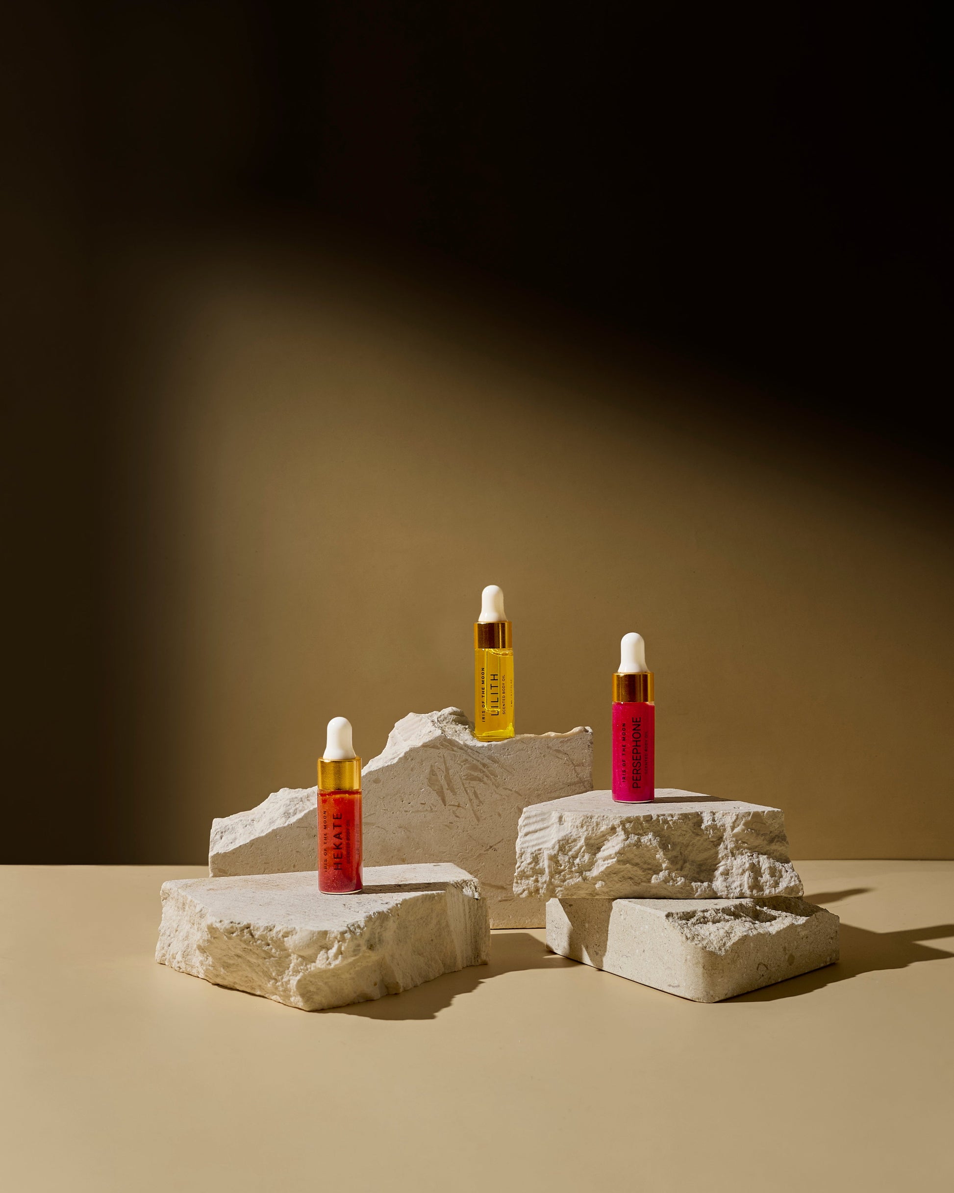 Three skincare bottles on stone blocks against a dark background