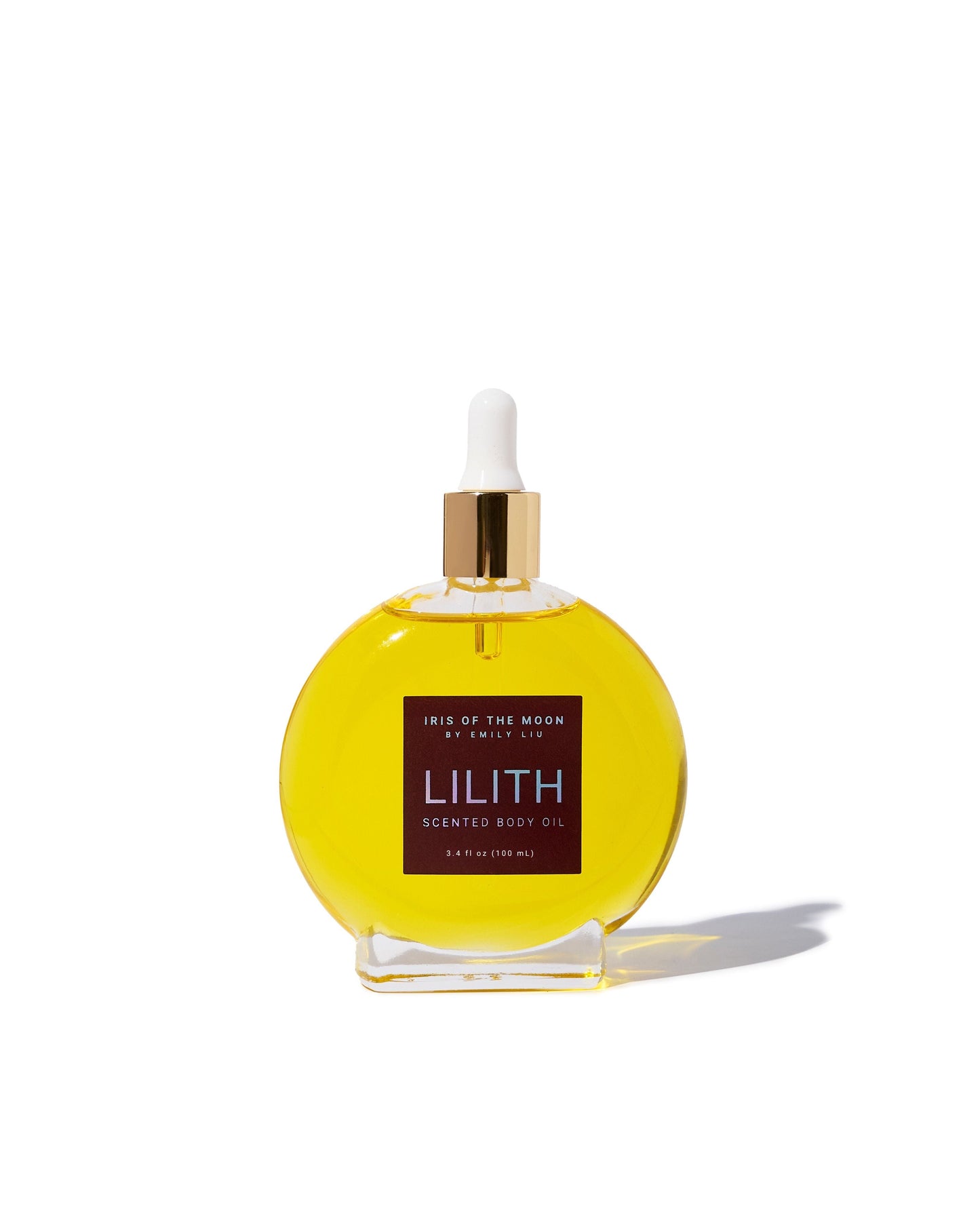A circular glass bottle filled with bright yellow "Lilith" scented body oil is centered against a clean white background, featuring a gold cap and a white dropper.