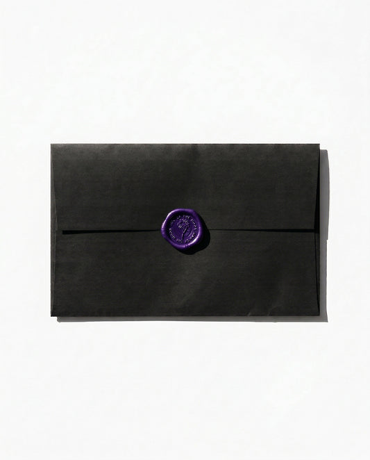 Black paper envelope with a dark purple wax seal against a white backdrop.