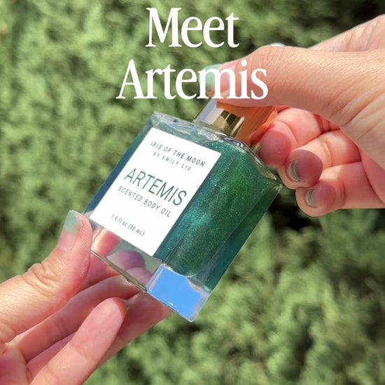 Close-up video featuring Artemis 30 mL body oil glass dropper bottle displayed against a dark evergreen background.