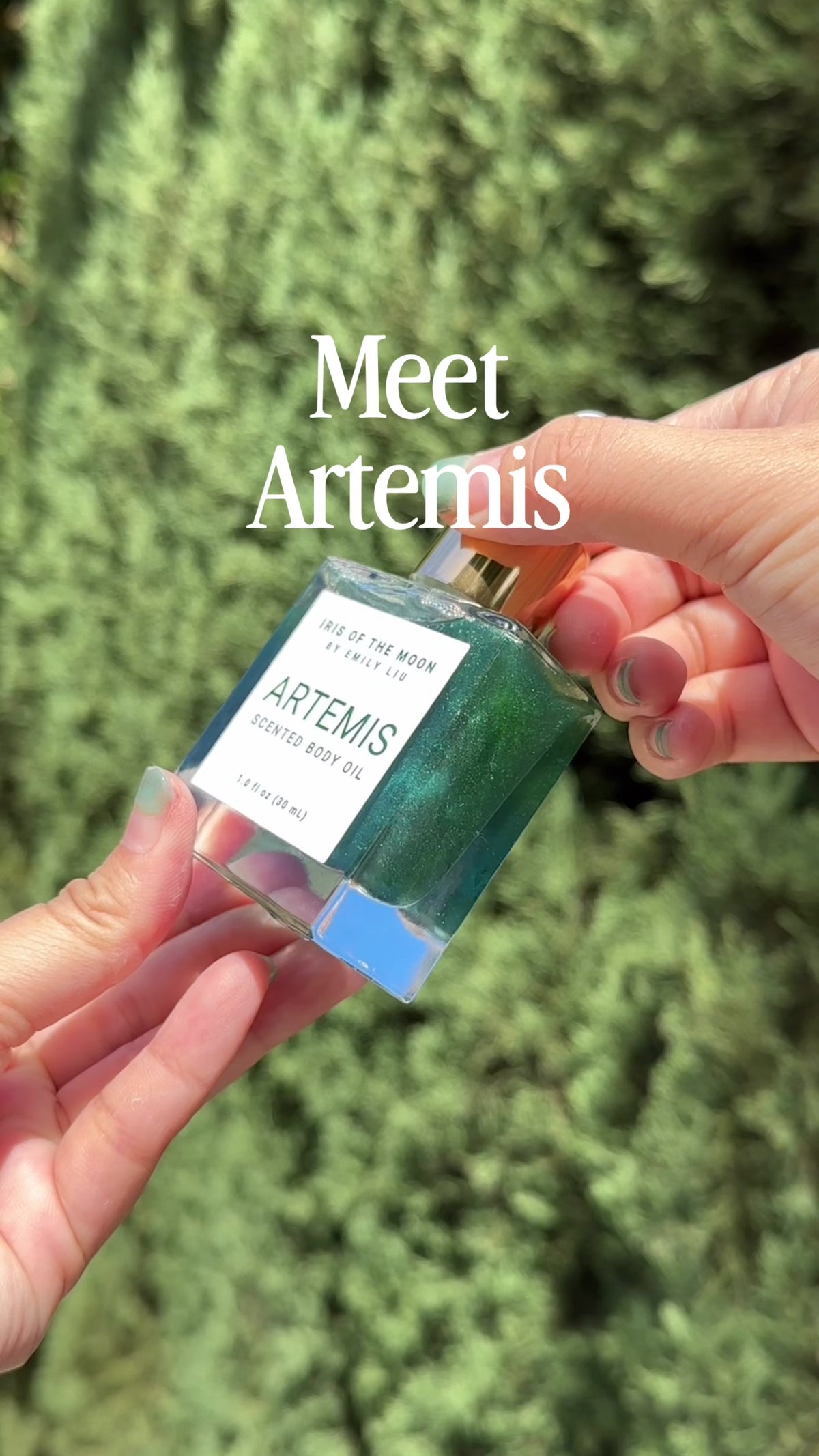 Close-up video featuring Artemis 30 mL body oil glass dropper bottle displayed against a dark evergreen background.